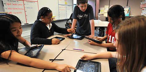 Students in middle school are collaborating to solve a problem using iPads